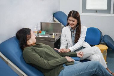 Güzel bayan doktor hastayı muayene ederken hastane odasında steteskop kullanır.