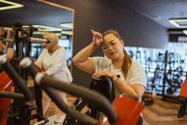 Asyalı bir kadının spor salonunda kardiyo çalışması.