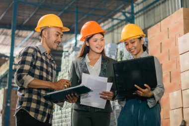 İş kadını ve fabrika işçisi veriye bakarken ve malzeme deposunda bir dizüstü bilgisayar kullanırken