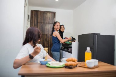 Mutfakta yemek pişiren ve eğlenen üç kadın grubu.