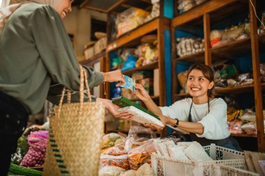 Mutlu yeşil market satıcısı müşterisiyle alışveriş yapıyor.