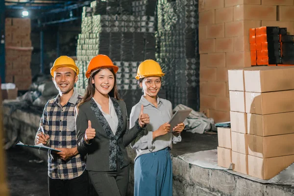 Güzel bir iş kadını ve şirket çalışanı depoda başparmaklarını gösterirken gülümsüyor.