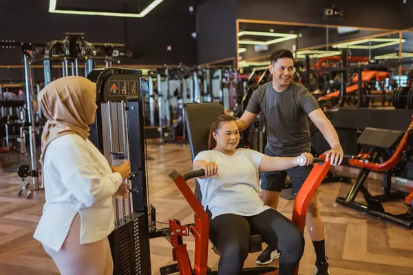 asian woman getting trained by personal coach in the gym