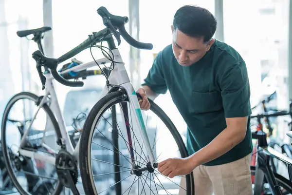 male employee installs a bicycle tire while working to assemble bicycles at a bicycle shop