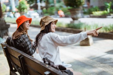 Kadın turist sohbetleri, parmak işaretleriyle bir arkadaşına yürüyüşten sonra oturmasını söyler.