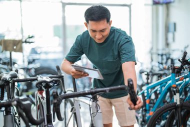 Bisikletçi dükkanında bisiklet tutacağı denerken ped kullanan genç adam.