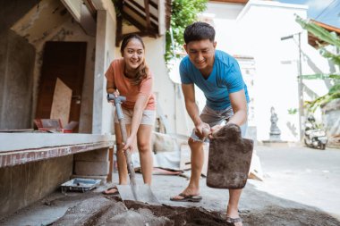 Mutlu genç karı koca ev yapmak için çimento karışımı yapıyorlar.