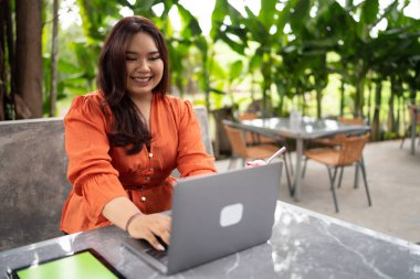 Ayrıca açık kafede dizüstü bilgisayar ve tablet kullanarak çalışan boyda bir kadın.