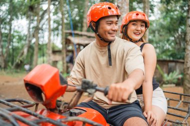 Mutlu Asyalı kadınlar kameraya bakıp gülümserken ATV 'deki ortağıyla birlikte ATV' ye biniyorlar.