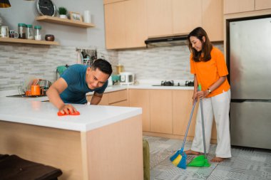 Asyalı erkek ve kadın birlikte mutfağını temizliyor.