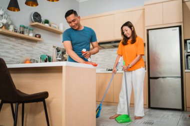 Asyalı adam mutfakta yemek masasını siliyor. Düşük açılı.