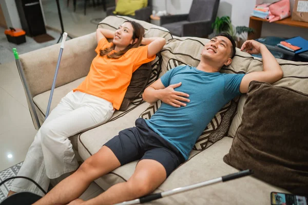 Asiatische Paar Legt Sich Auf Sofa Nach Dem Putzen Das lizenzfreie Stockbilder