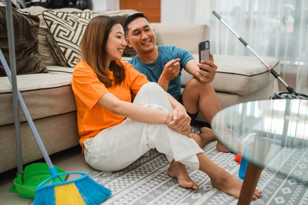 Pasangan Asia Menonton Sesuatu Telepon Setelah Housekeeping Bersama Sama Stok Gambar