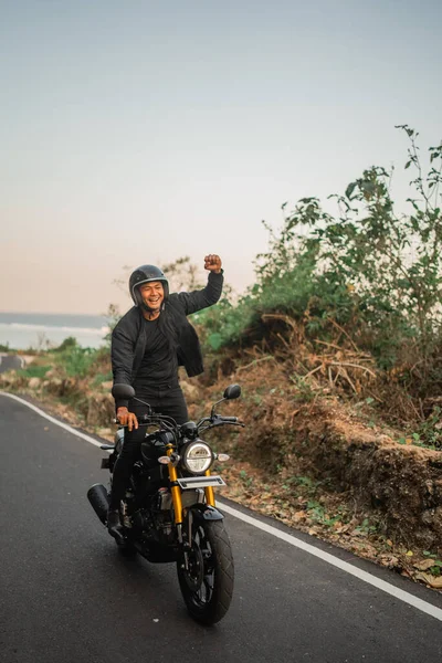 Indonesischer Fahrer Steht Beim Motorradfahren Mit Faustpumpe Geste lizenzfreie Stockfotos