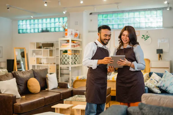 two shop owners using a tablet together standing in a furniture shop