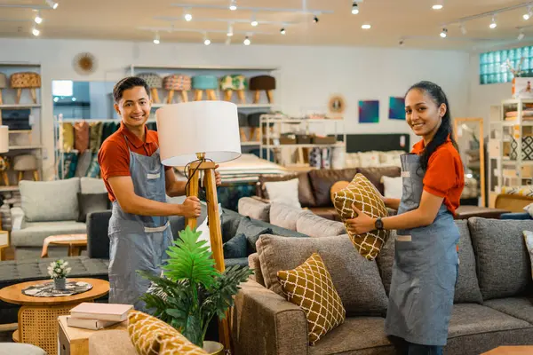 shop assistants in apron with their friend working to tidy up the furniture store