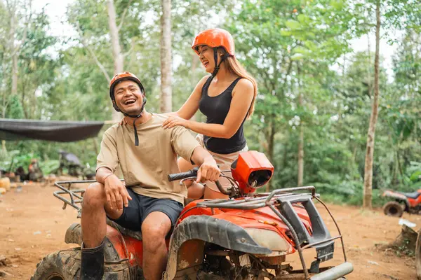 asian woman holding the shoulder of the asian man while joking together at atv tracking arena