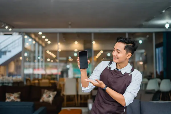 Mobilya Mağazasının Önünde Telefon Ekranını Gösterirken Hareketi Yapan Önlüklü Bir Telifsiz Stok Imajlar