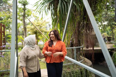 Kafiyeli iş kadını, iş arkadaşıyla dışarıda kafeteryada dolaşırken sohbet etti.