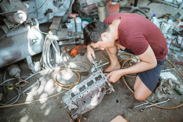 Mechaniker Reinigt Einen Zylinderkopf Mit Einem Staubwedel Während Einen Motor Stockfoto