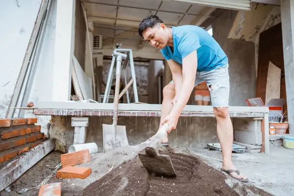 Asian Man Doing Construction Work Mixing Cement Sand Using Hoe Stock Photo