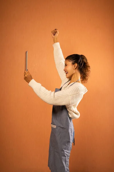 Excited Asian Girl Wearing Apron Raised Fist While Using Tablet Royalty Free Stock Photos