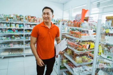 Erkek işçi, elinde minimarket bir panoyla ayakta duruyor.