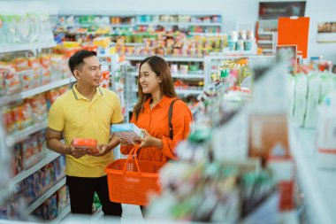 Genç çift alışveriş yapıyor, karı koca süpermarketten alışveriş malzemeleri seçiyor.