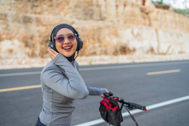 neşeli tesettürcü bisiklet sürerken müzik dinlemekten zevk alıyor