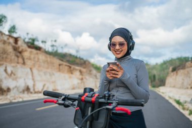Bisiklet sürerken telefon kullanan tesettürlü kadın, bisiklet konsepti