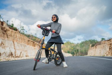 Yollarda tesettürlü neşeli bir kadın, sağlıklı yaşam tarzı, bisiklet konsepti.