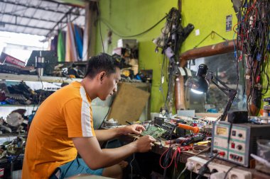 Asyalı teknisyen servis istasyonunda elektronik devreyi tamir ediyor.