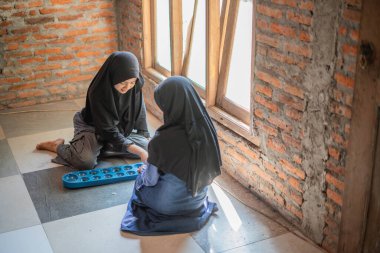 Genç tesettürlü kızlar içeride geleneksel Congklak Endonezya oyunları oynuyorlar