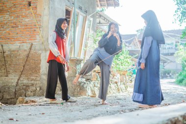 Mutlu tesettürcü çocuklar ip atlarken evin dışında