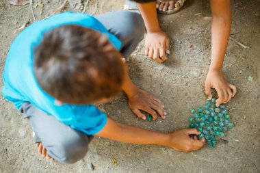 Asyalı çocuklar geleneksel oyunlar oynamak için yerde misket oynuyorlar.
