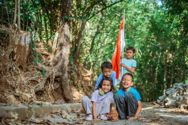 Dışarıda oynarken elinde ulusal bayrak tutan Endonezyalı bir çocuk.