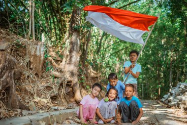 Köyde geleneksel oyunlar oynarken elinde Endonezya bayrağı sallayan bir grup çocuk.