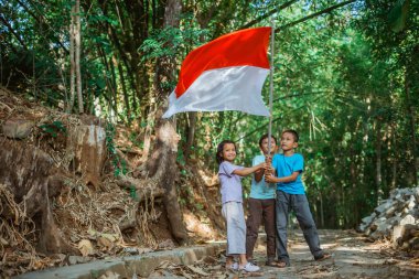 Asyalı çocuklar dışarıda oyun saatlerinde ulusal bayrak sallıyorlar.