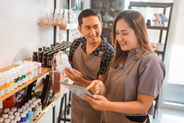 ayakkabıcıda tablet kullanarak sergilenen ürünleri kontrol eden işçiler