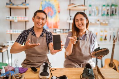 Ayakkabı temizleme işçisi işaret eden ekranlı telefonu tutuyor.