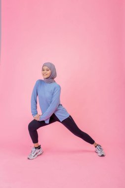 Renkli giyimli genç bir kadın zarif bir şekilde esneyip güç ve esneklik gösteriyor.