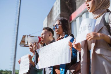 Çeşitli aktivistlerden oluşan bir grup, canlı bir ortamda sosyal adaleti tutkuyla protesto ediyor.