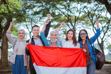 Endonezya bayrağını elinde tutan genç öğrenciler açık havada yumruğunu kaldırdı.