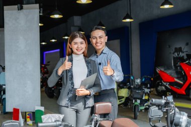 Elektrikli bisiklet galerisinde elinde tabletle ayakta duran iş adamları.
