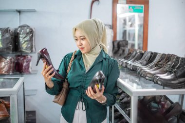 Deri mağazasında resmi deri topuklu ayakkabı seçen kadın tesettür müşterisi