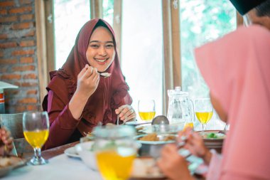 Evde bayram kutlaması için ailesiyle yemek yerken gülümseyen bir anne.
