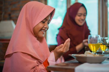 Geleneksel kıyafetli iki kız sıcak bir yemek yemeden önce keyifli bir anı paylaşıyorlar.