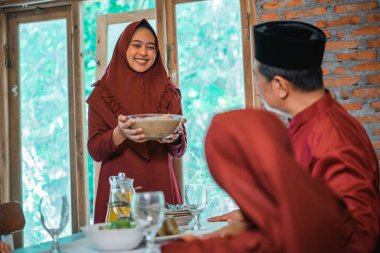 Asyalı Müslüman anne yemek odasına iftar için bir kase komposto getiriyor.