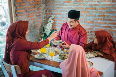 Neşeli bir aile, uyum içinde geleneksel lezzetli bir yemeğin tadını çıkarıyor.