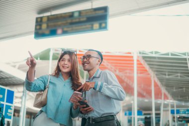 Heyecan ve neşe dolu bir çift, havaalanında heyecanlı yolculuklarını planlıyorlar.